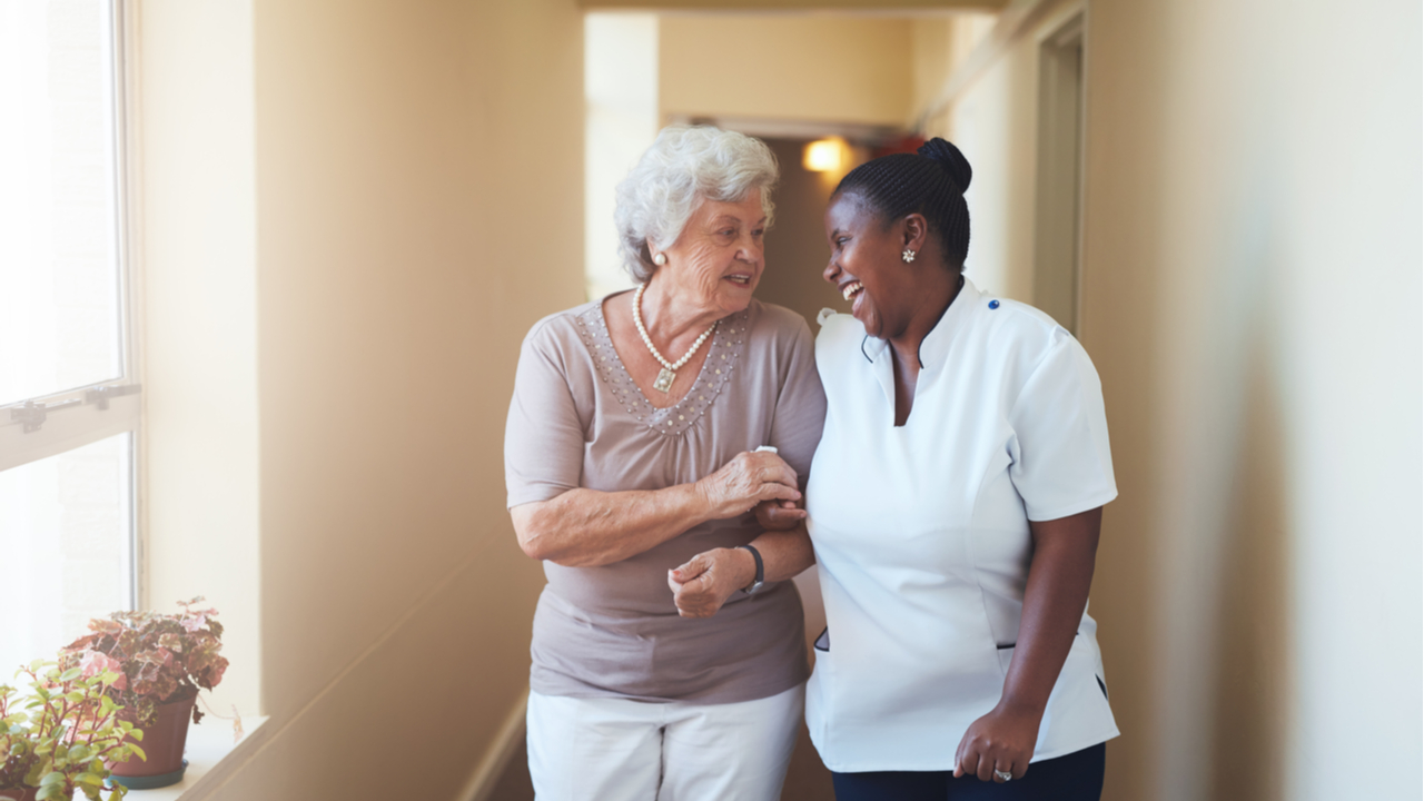 An elderly woman smiling while speaking to a nurse. Depicts one-on-one attention