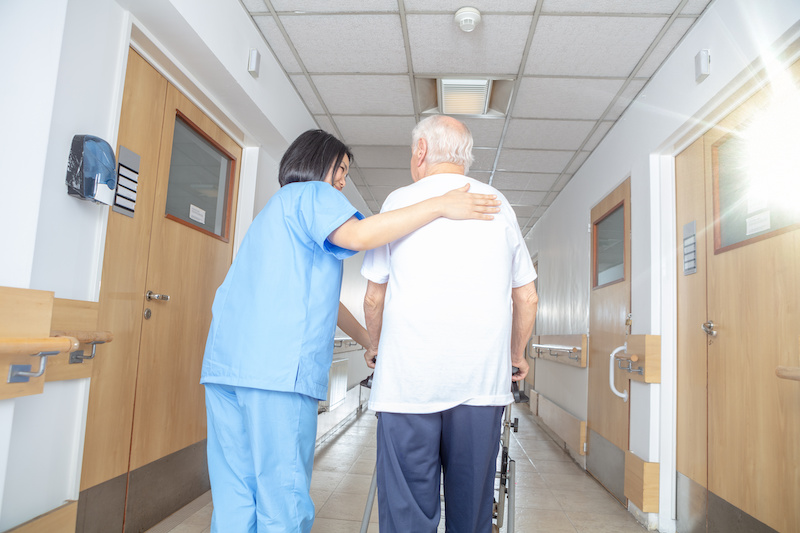 Nurse helping senior walk in the hospital