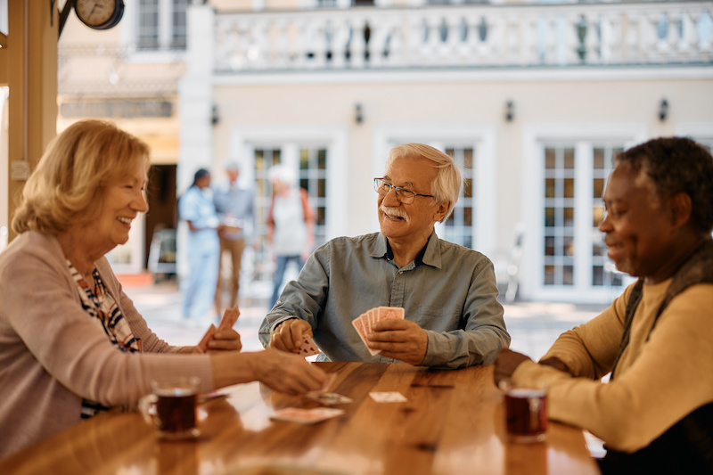 Three people in senior living playing cards having a good time