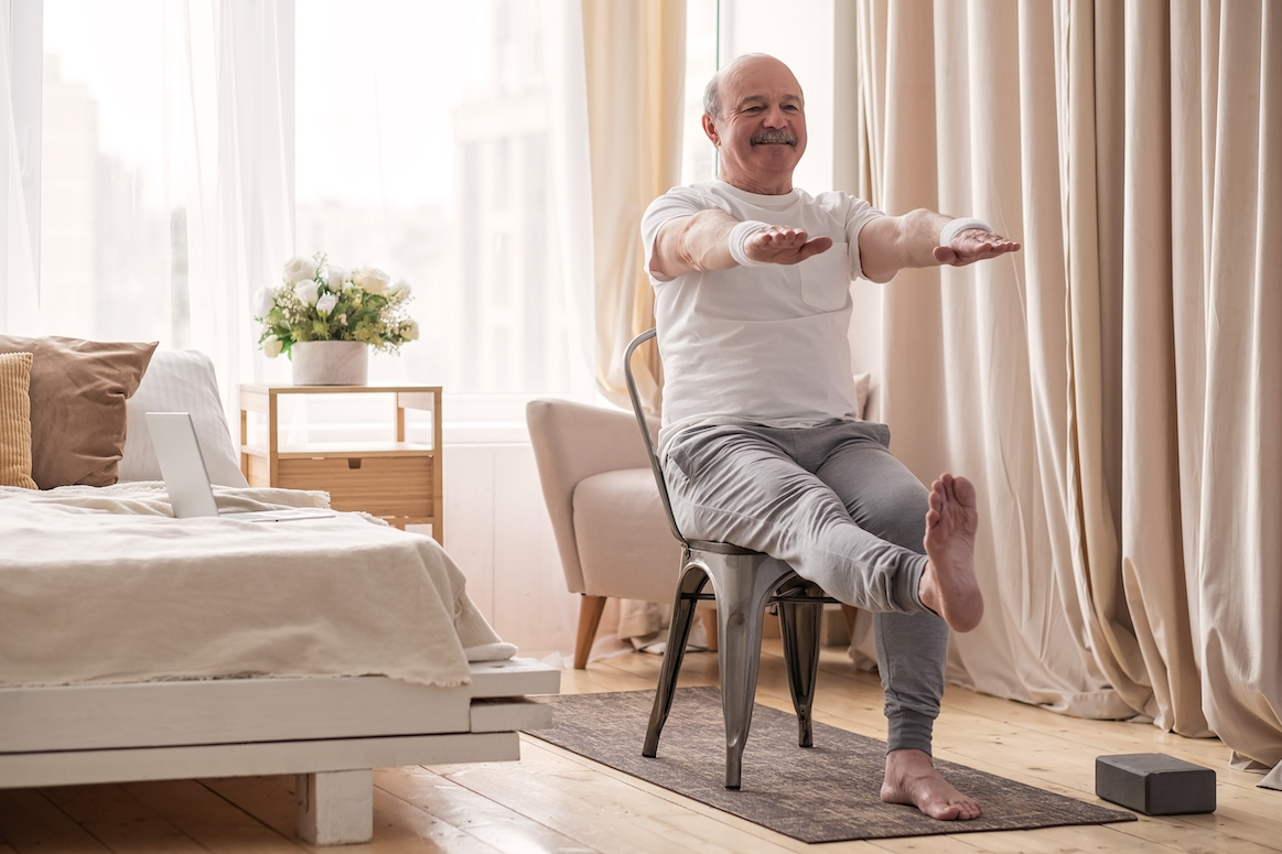 Elderly man squat exercise for legs and hands on chair